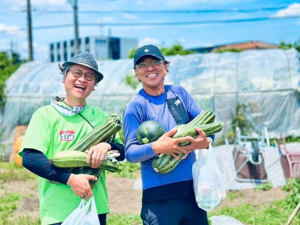 畑で収穫した野菜を持つ生産者たち